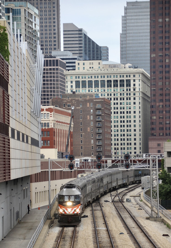 Commuter train on three-track line surrounded by tall buildings 