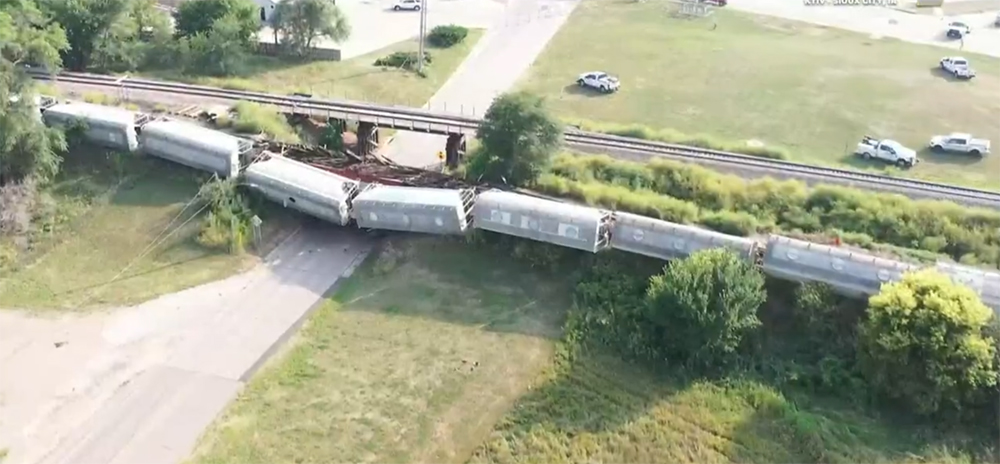 Overturned covered hoppers, with some hanging off a bridge