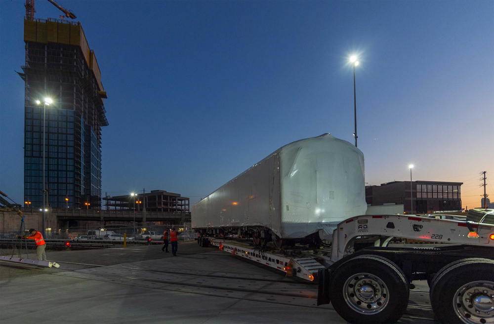 Subway car in protective wrap is delivered by truck