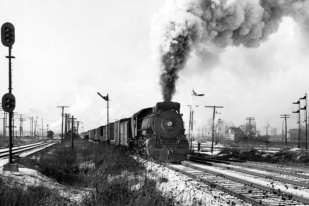 Smoking steam locomotive among many railroad signals