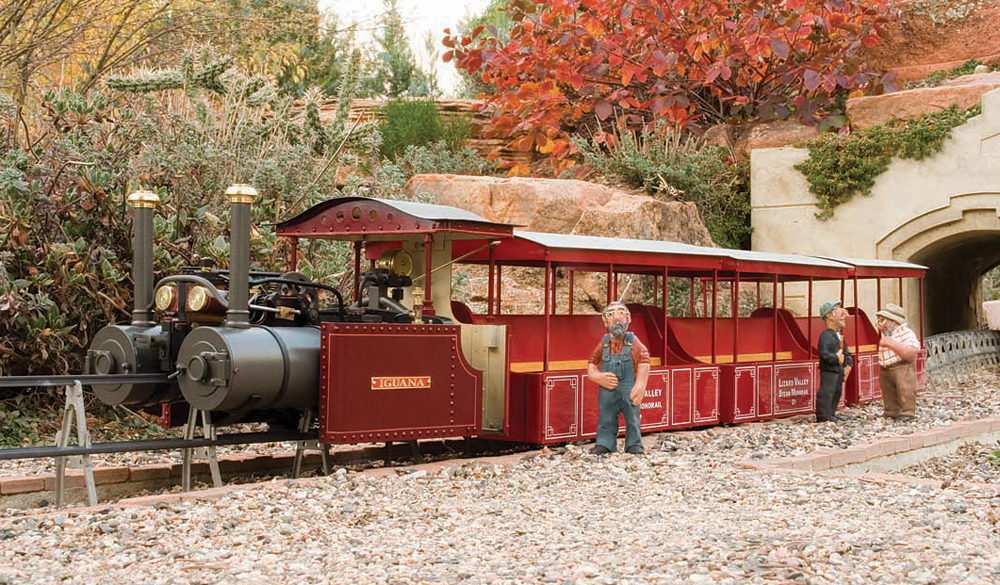 maroon tram engine near tunnel on garden railway