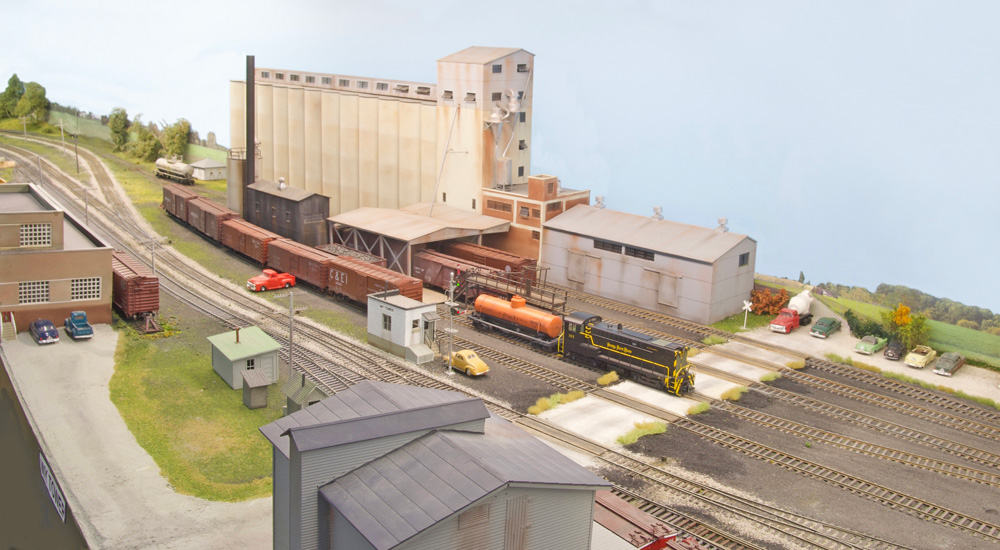 A diesel locomotive switches a large grain elevator against the backdrop of an HO scale layout
