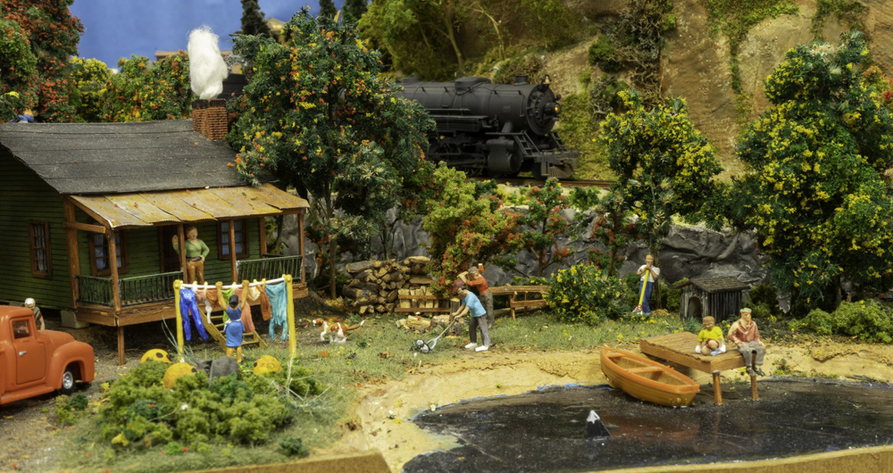 The Grand Strand Western Railroad layout: A scene on a model railroad layout with a family homestead and a train in the background