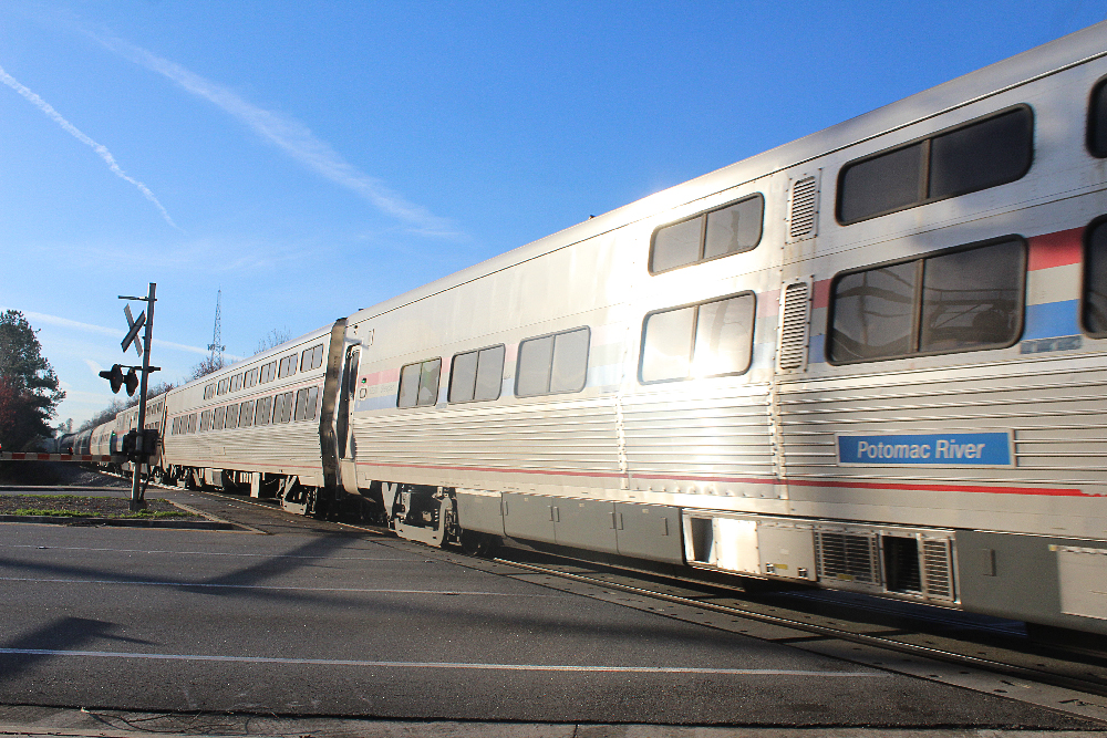 Silver passenger train in grade crossing. Amtrak goes outside for new chief commercial officer.
