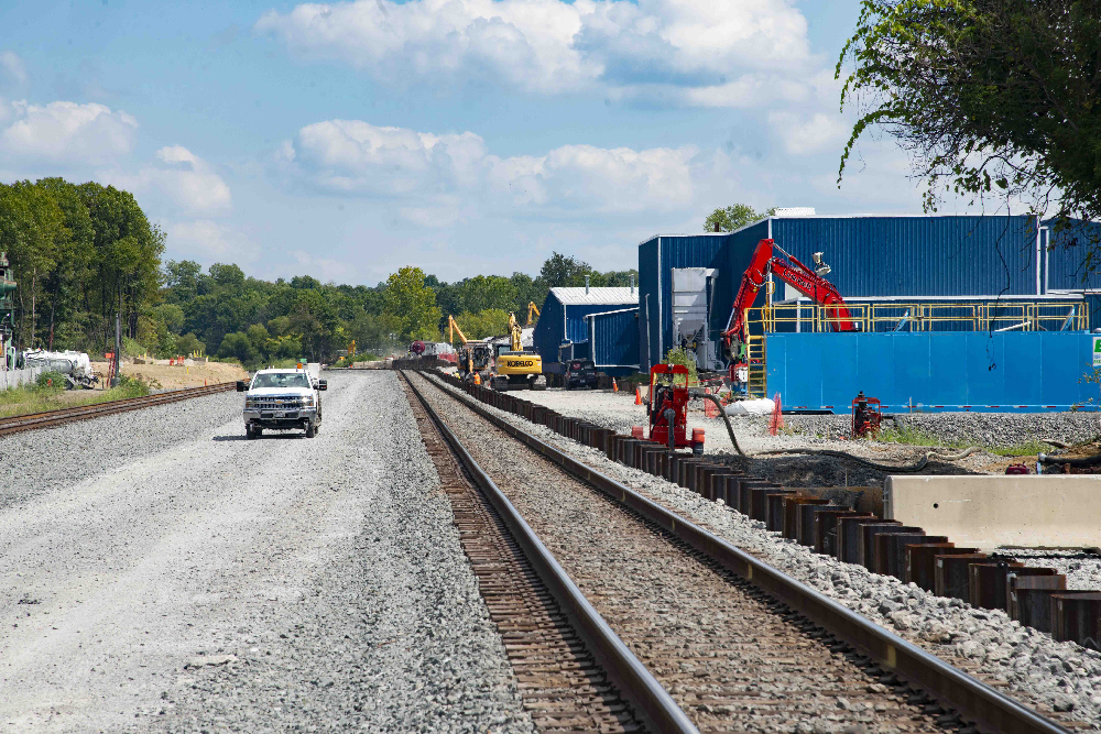 Gravel road and train track with excavator in background.