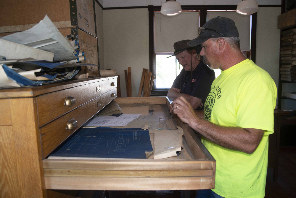 Two men looking in drawer of a map case. EBT wins $10,000 federal grant to preserve archives.