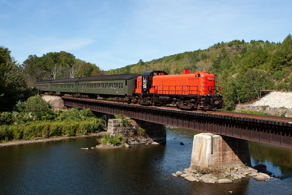 orange locomotive pulling green passenger cars