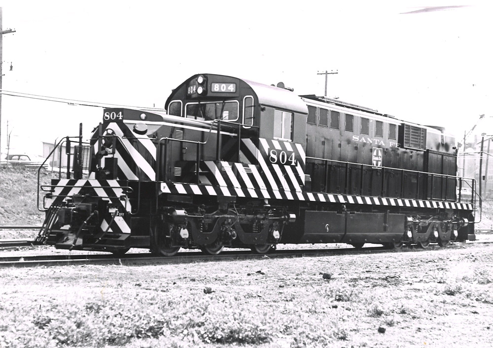 A black and white three-quarter view of a black-painted locomotive with light diagonal stripes.