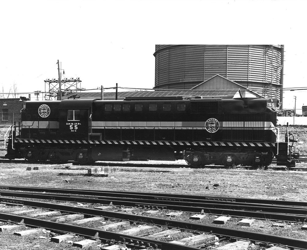 A sideview, in black and white of a rail yard with a locomotive in middle distance