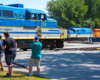man photographing side of blue, yellow, and gray locomotive