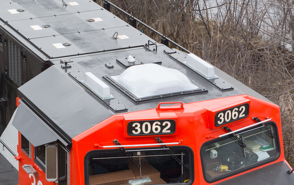 White antenna housings cover the gray-painted roof of a modern diesel locomotive.