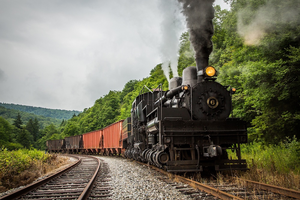 Giant geared steam locomotive pulls a freight train.