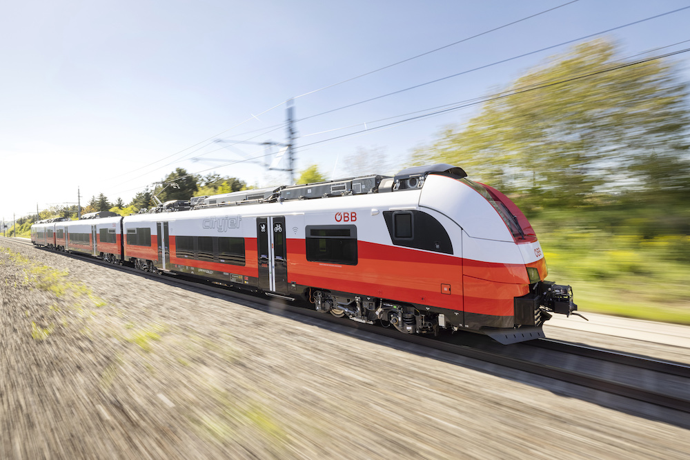 Modern commuter train racing past camera.