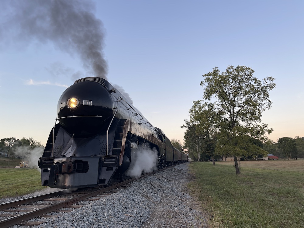 Streamlined steam locomotive operating during early evening.