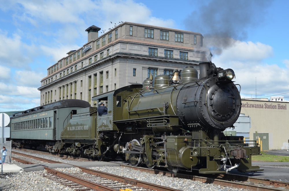 Green steam locomotive pulls passenger train.