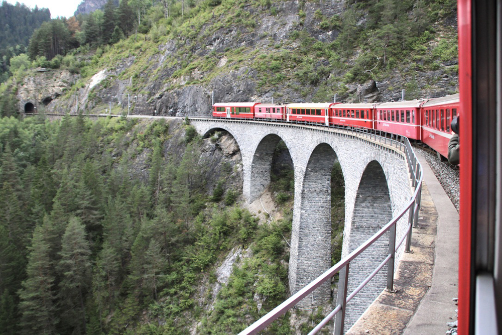 Red train on huge stone bridge
