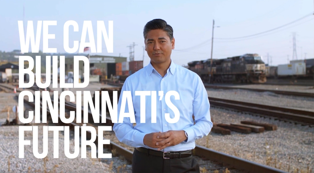 Man standing at rail yard with caption reading "We can build Cincinnati's future."