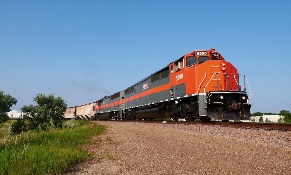 Low-angle view of two locomotives and train of covered hopers