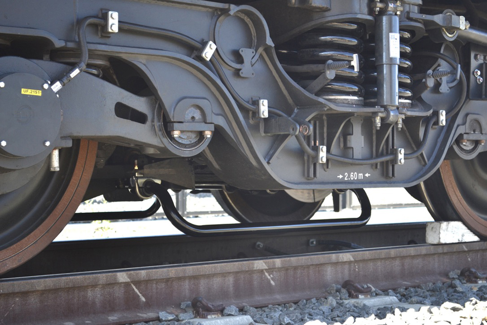 Closeup of locomotive wheelset with antenna mounted next to rail.