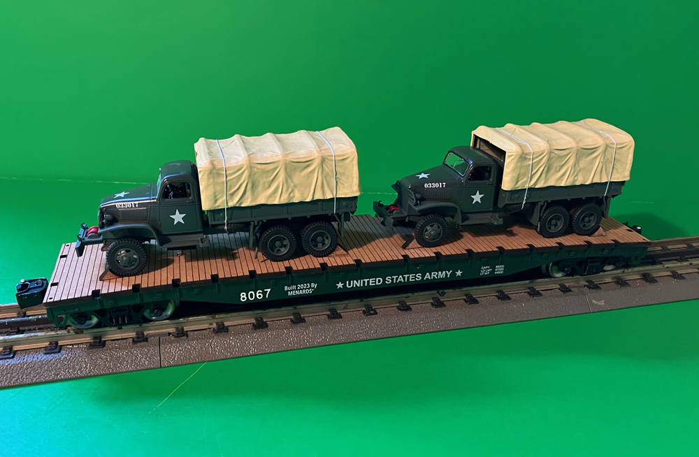 two army trucks on model flatcar