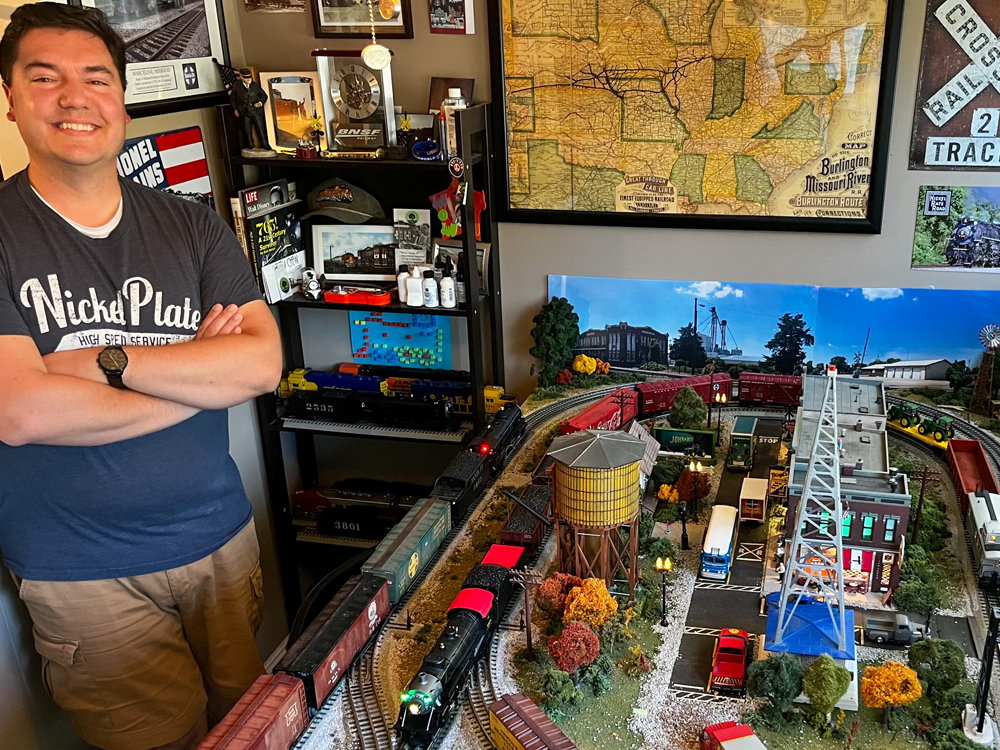 man standing next to train layout