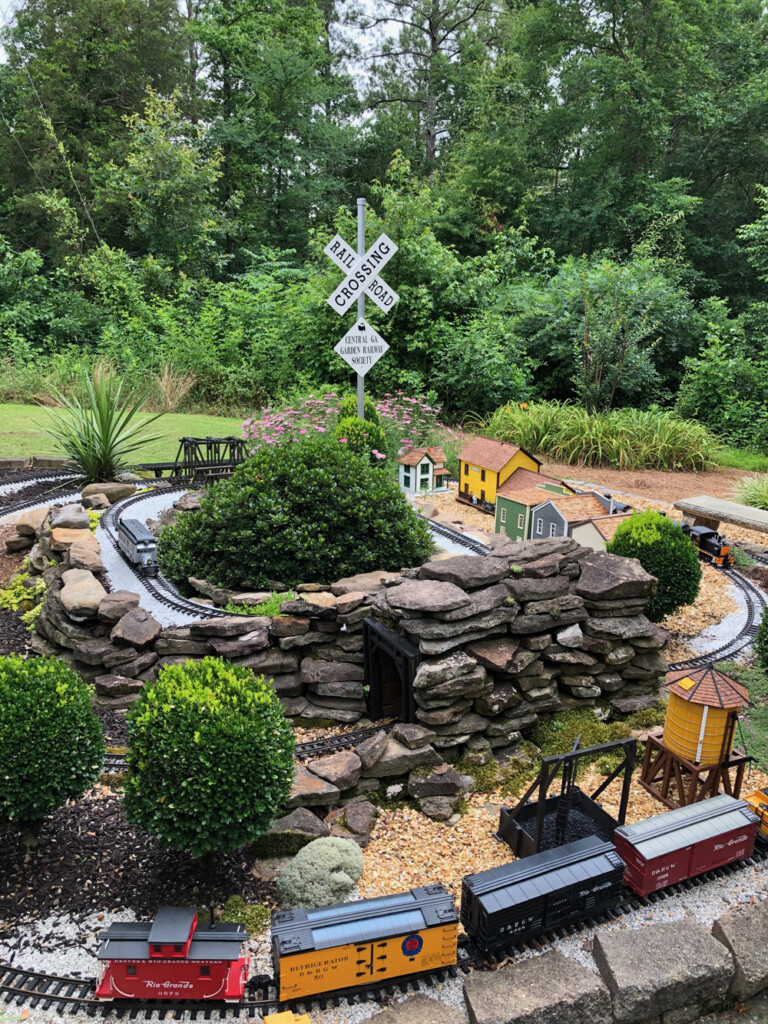 overview of a garden railway with full-size crossbucks behind it