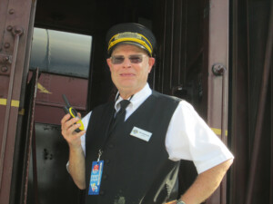 Man holding walkie-talkie near cab of locomotive