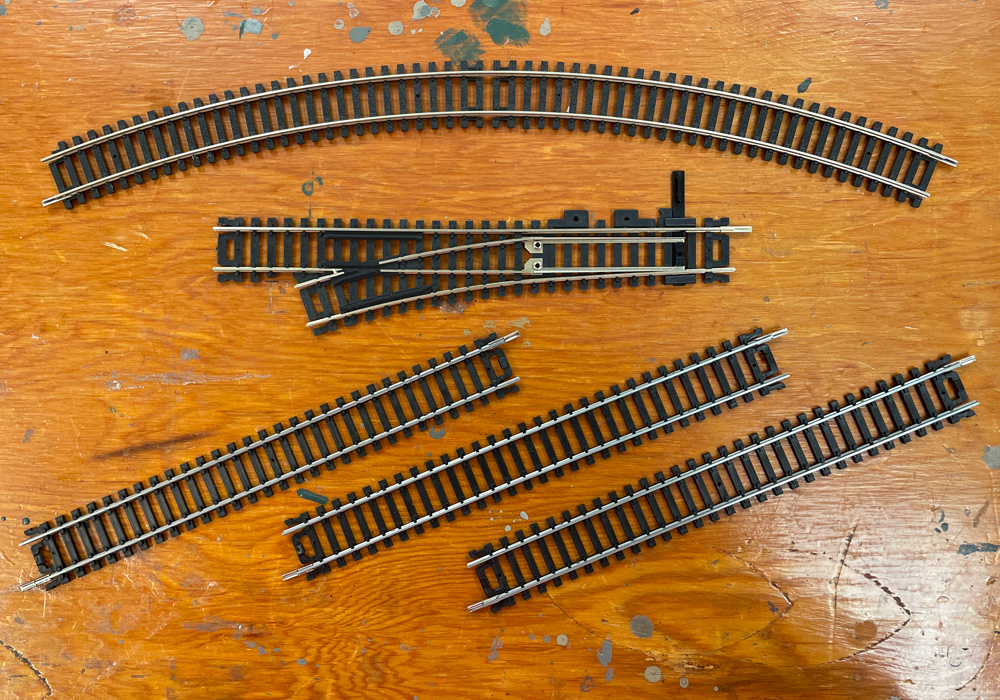 Three straight pieces of sectional track, a sectional curve, and a turnout on a wood tabletop