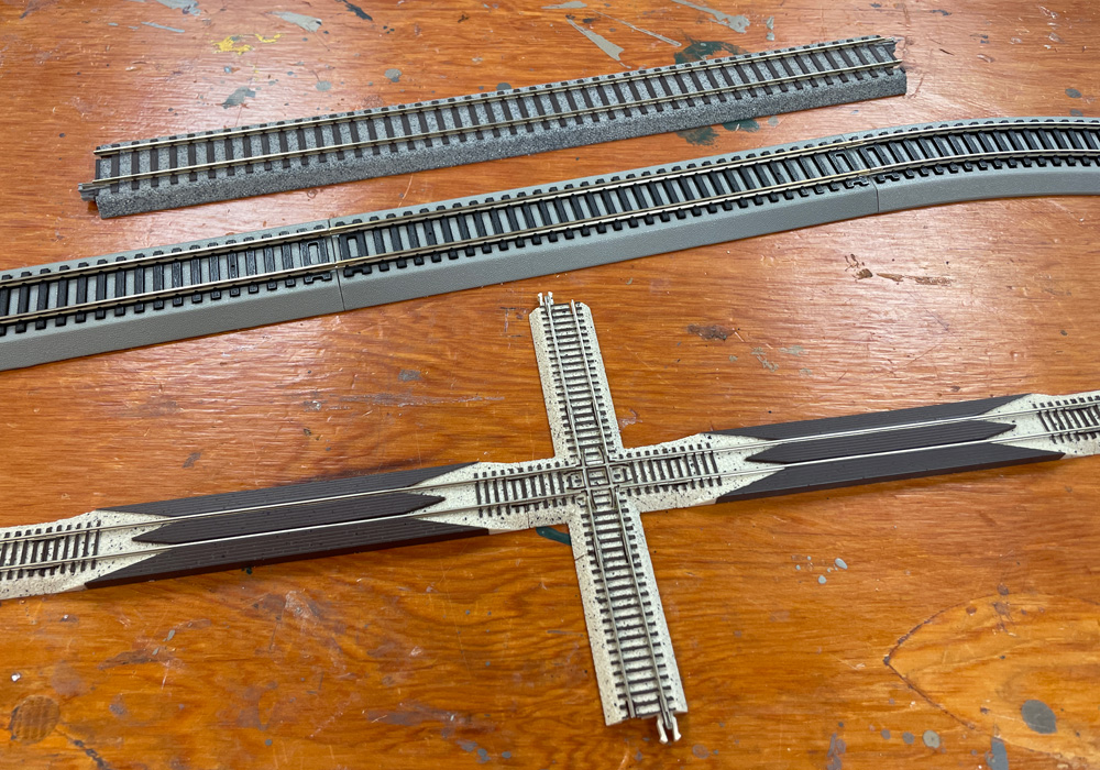 Several pieces of sectional track with attached plastic roadbed on a wood tabletop
