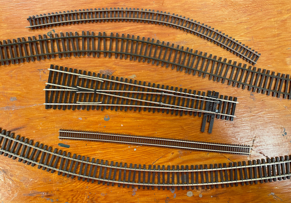 Several pieces of straight and curving track in different scales on a wood tabletop