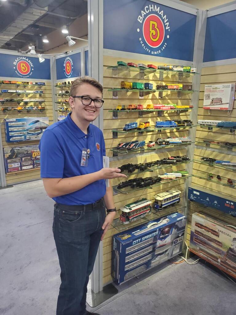 Man smiles next to shelves full of model trains