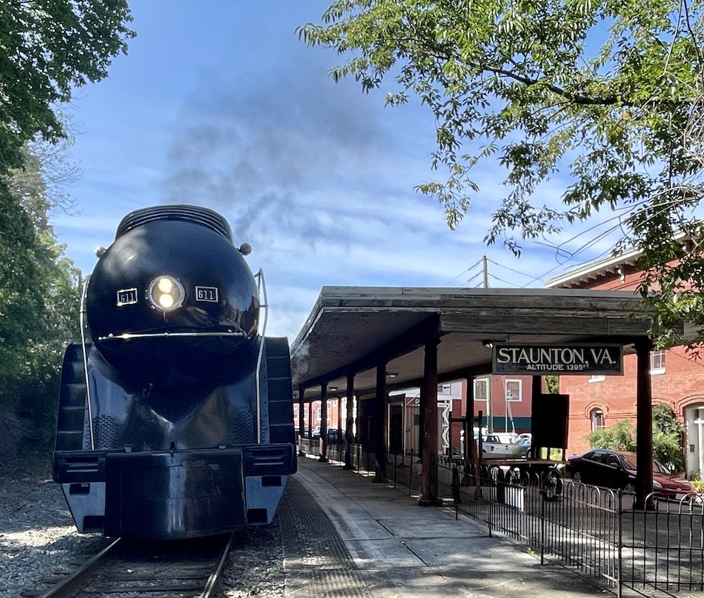 Streamlined steam locomotive arriving at historic train station.