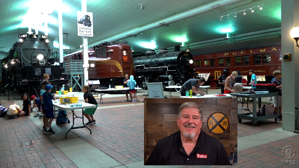 Large room with full-size trains and children working at tables. Making friends at summer railroad camp.