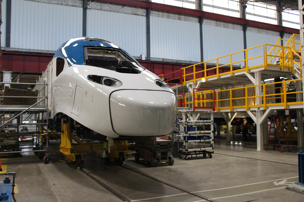White and blue power car for high-speed train on factory floor