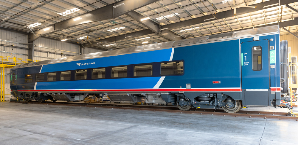 Passenger car with two-tone blue paint scheme inside building