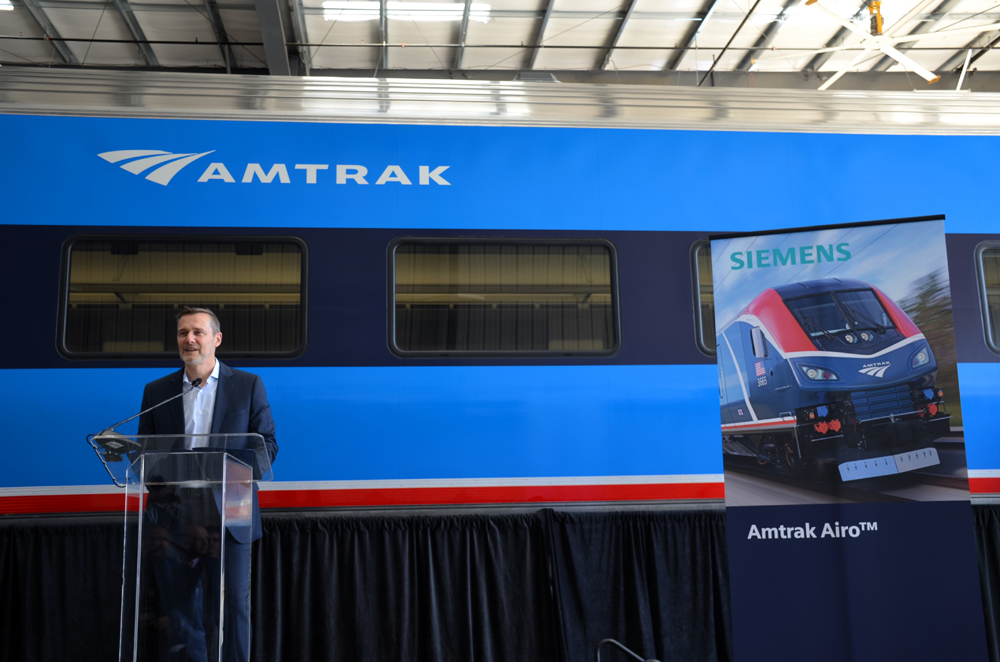 Man speaking in front of passenger car