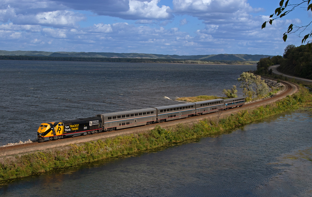 Passenger train with locomotive, three bilevel cars, and single-level car.