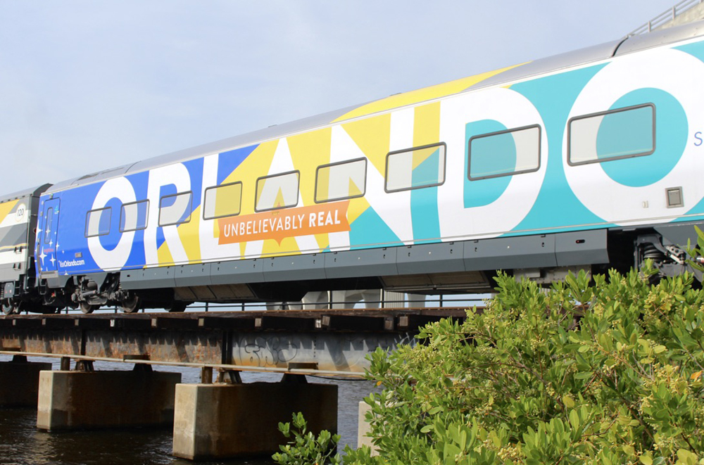 Passenger car wrapped with advertising including the word "Orlando" in large letters.