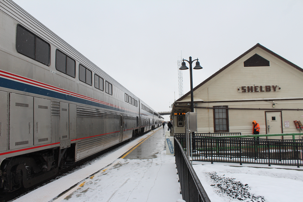 Passenger train at station with snow on the ground.