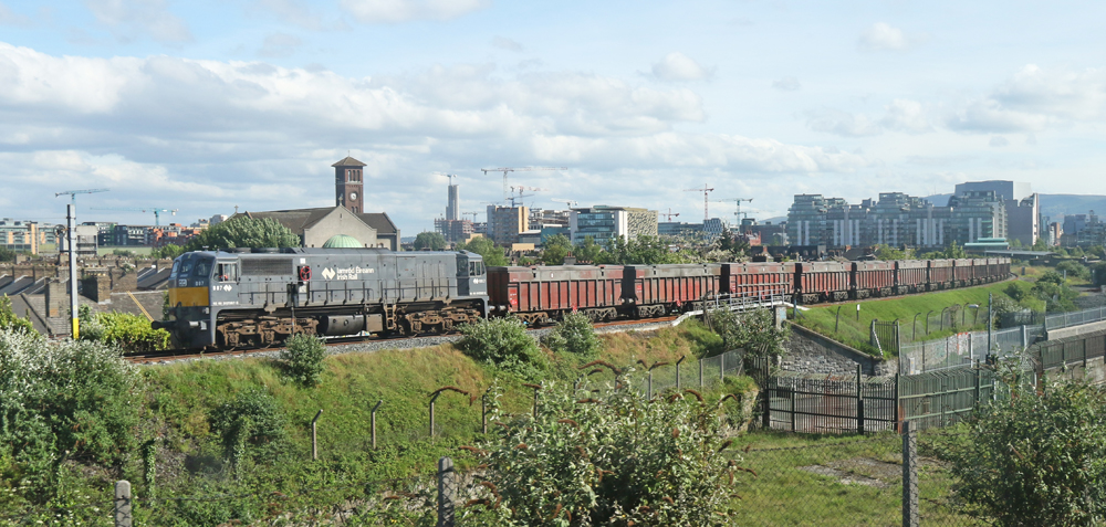 Gray locomotive pulling string of gondola cars