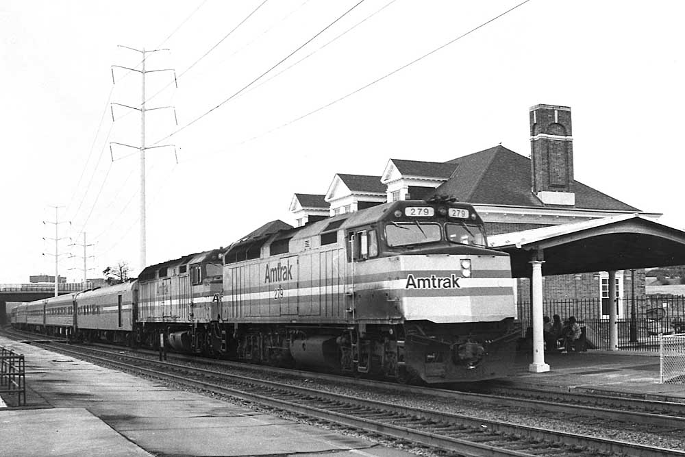 overnight Amtrak trains in front of brick station under power lines