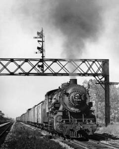 Steam locomotive with Chicago & North Western freight train under signal bridge