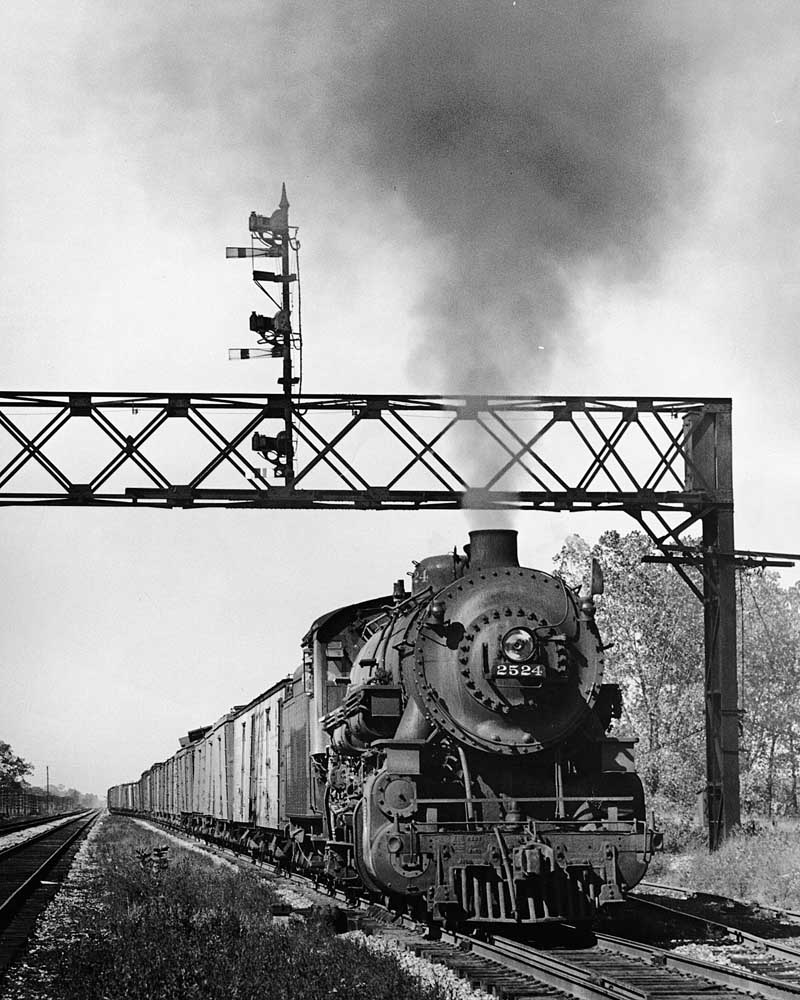 Steam locomotive with Chicago & North Western freight train under signal bridge