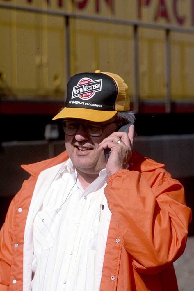 Man in shirt shirt and orange jacket using cell phone