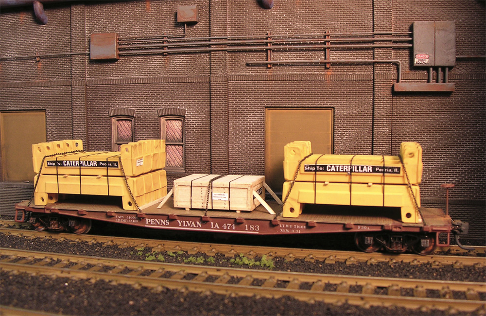 Three loads bundled with steel strapping on an HO scale flatcar