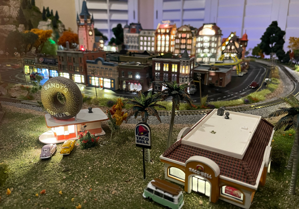 A model of a donut shop with a large donut lettered “Sandy’s Donuts” on the roof