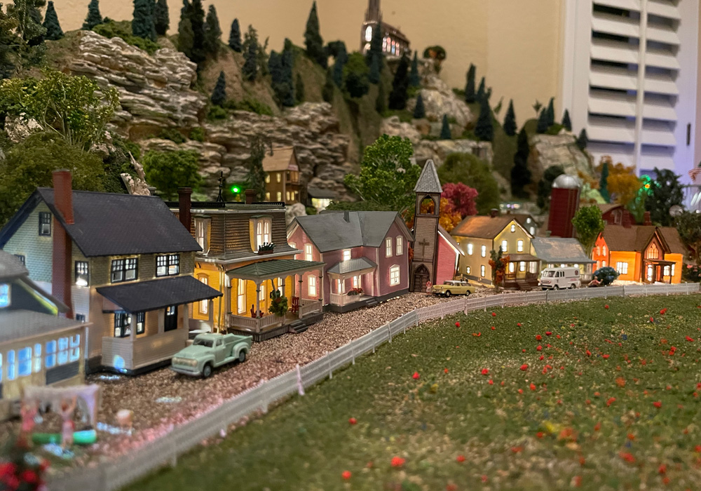 A row of illuminated houses stretch around a curving gravel road