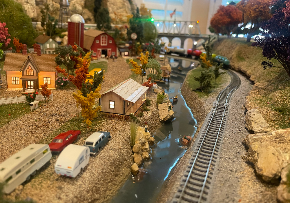 A creek winds alongside the track on an N scale train layout