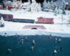 The tail end of a freight train rolls past a frozen pond with ice skaters
