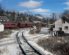 A dusting of snow lies across the track as a passenger train rolls by in the distance